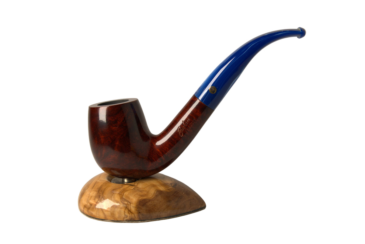 A smoking pipe with a glossy dark reddish-brown body and a curved blue stem, displayed on a carved wooden stand against a neutral gray background.
