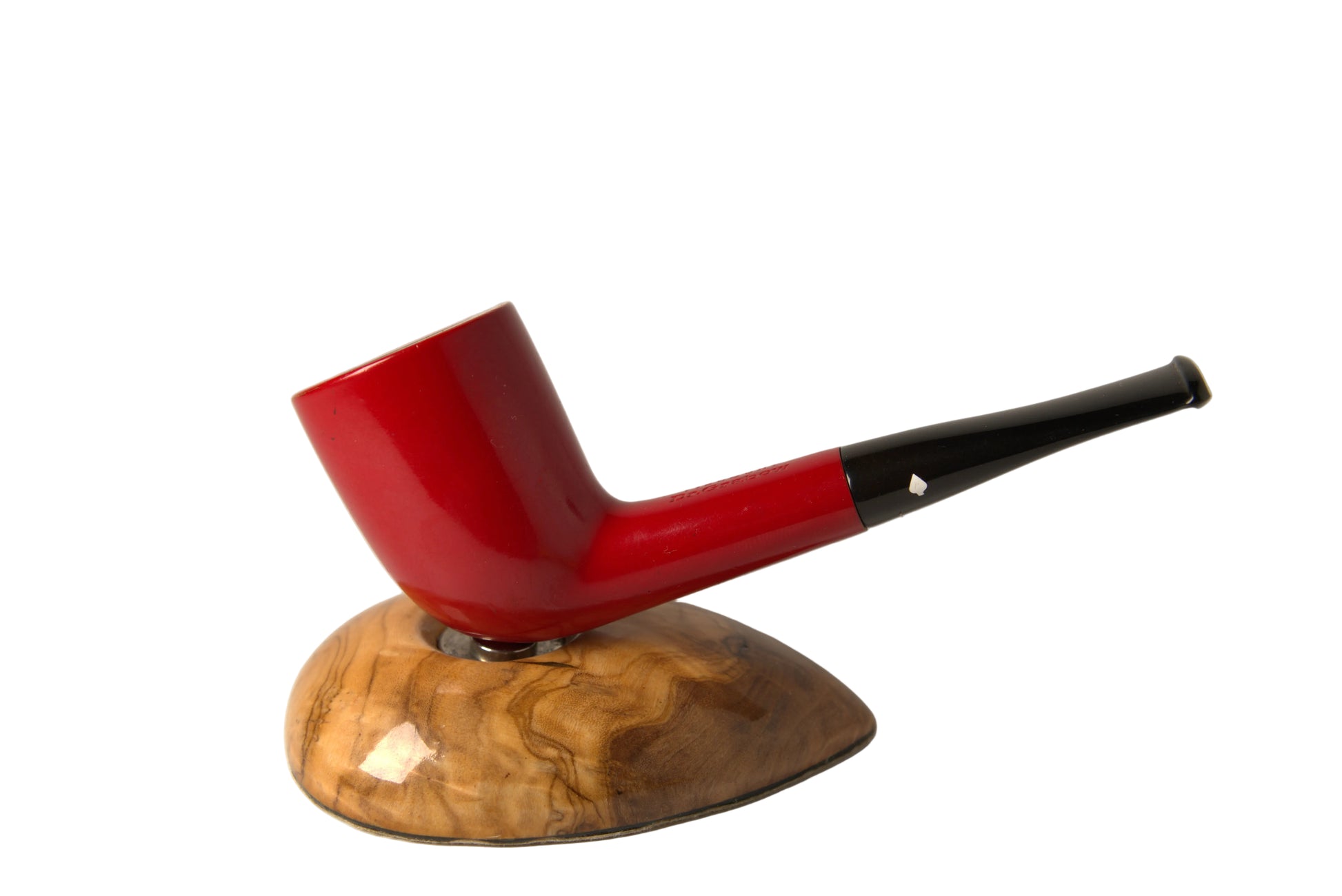 A red smoking pipe with a black stem, displayed on a polished wood stand against a neutral gray background.