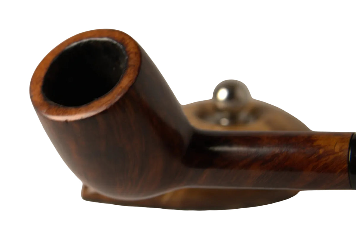 A close-up studio shot of a polished dark brown wooden smoking pipe resting on a small metallic stand against a neutral light gray background.