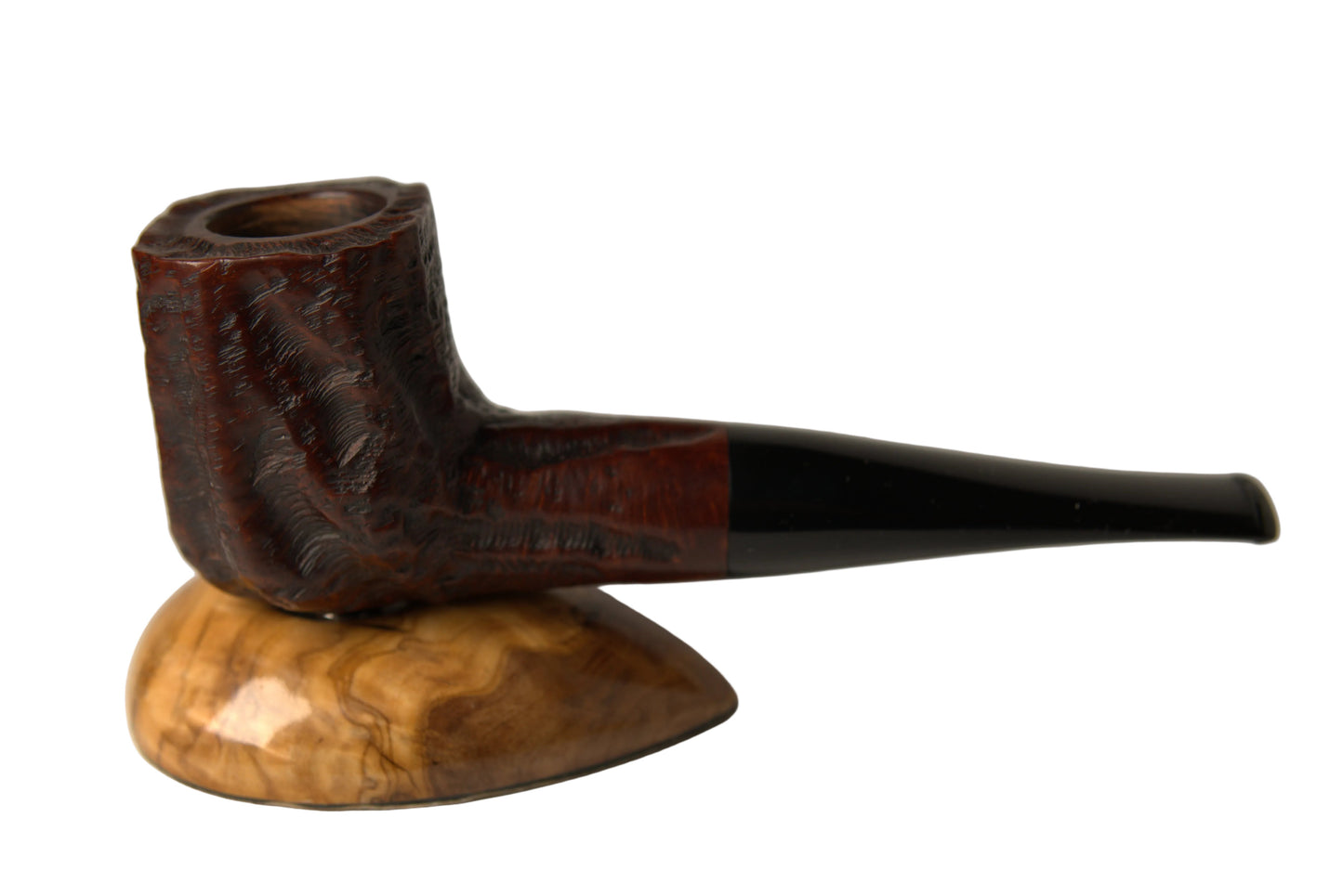 A carved smoking pipe with a dark brown textured bowl and a glossy black stem, displayed on a polished wood stand against a neutral gray background.