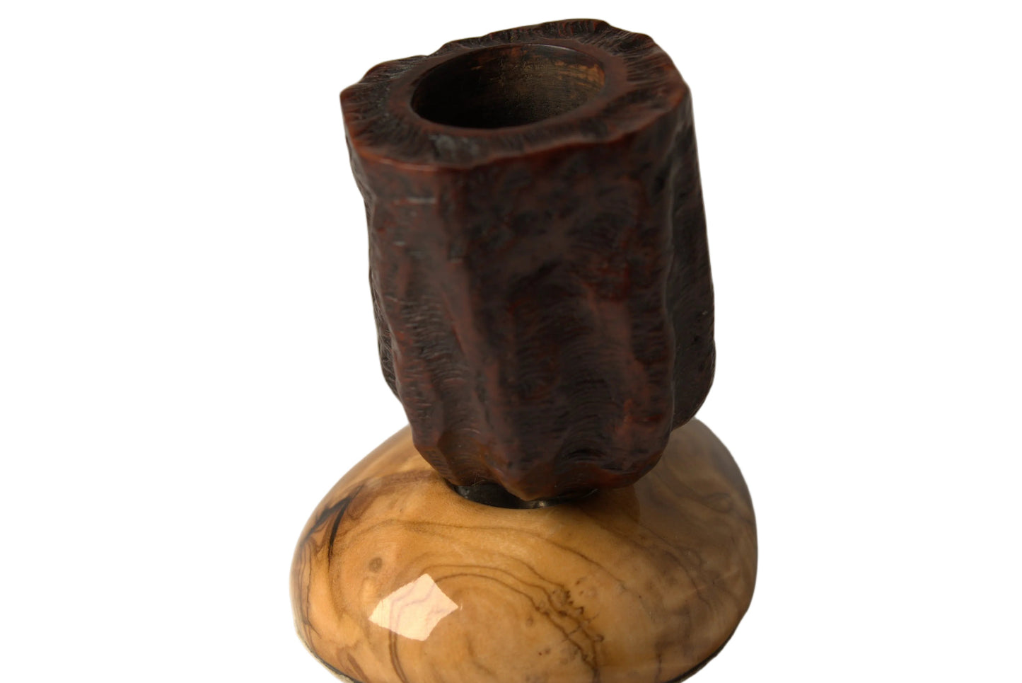 A sculptural wooden candle holder featuring a dark brown, textured cylindrical top mounted on a polished, swirling light brown wooden base, set against a neutral gray background.
