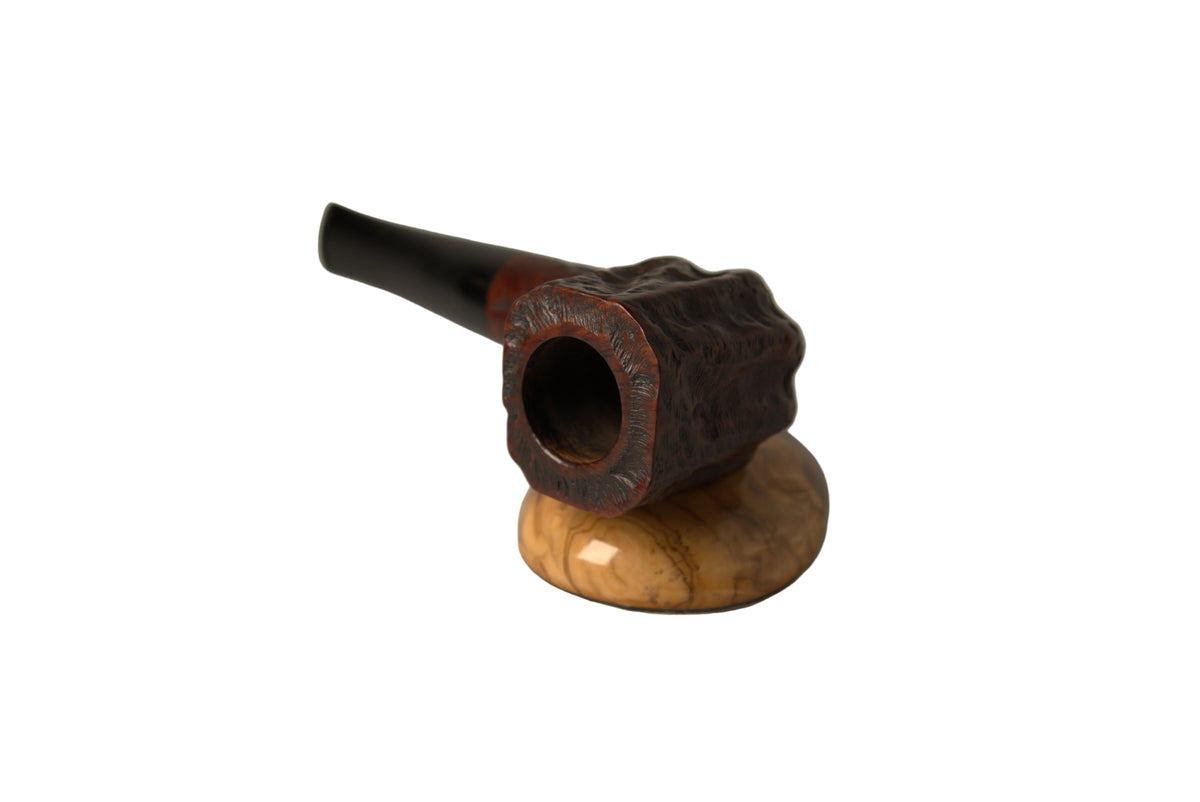 A smoking pipe with a dark carved wooden bowl and a glossy light brown wooden base, photographed on a neutral light gray background.