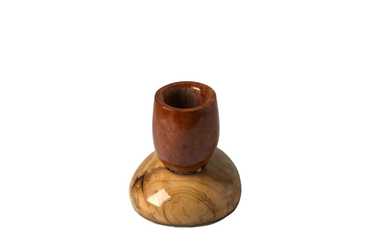 A smoking pipe with a polished reddish-brown wooden bowl mounted on a light tan and brown wood-grain base, photographed against a neutral light gray background.