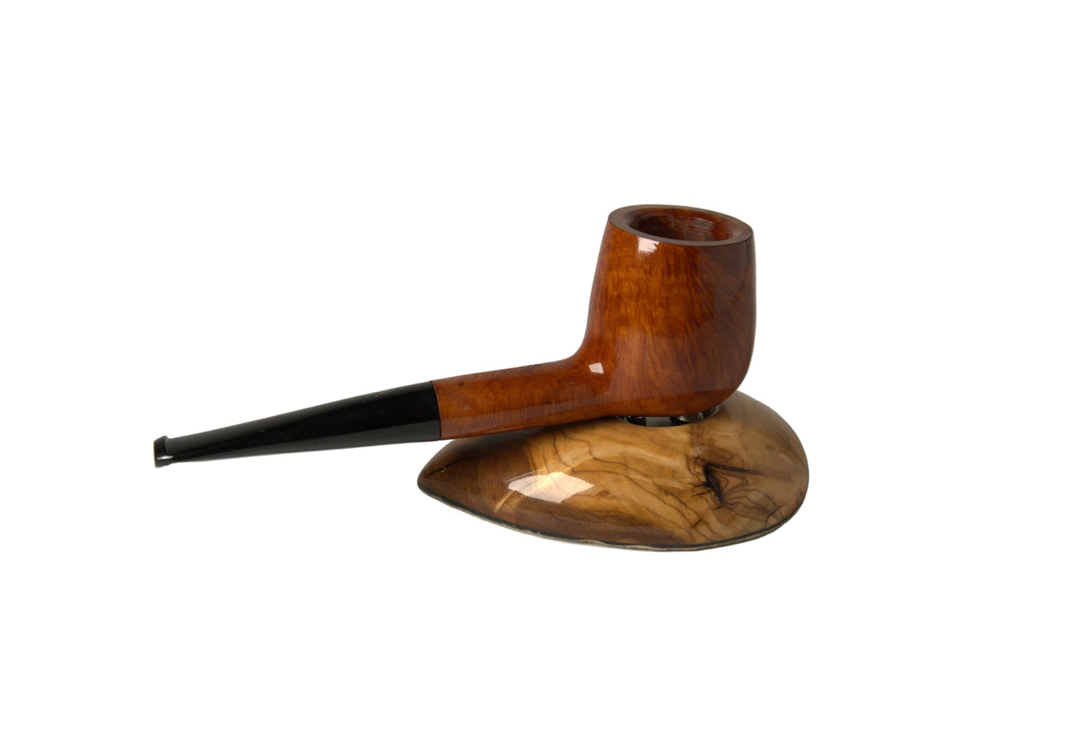 A polished wooden smoking pipe with a glossy brown body and a black stem, displayed on a carved wooden stand against a neutral gray background.