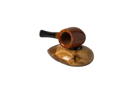 A polished wooden smoking pipe with a glossy reddish-brown bowl and a black stem, resting on a matching carved wooden stand against a neutral light gray background.