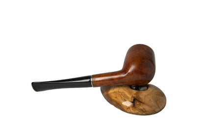 A polished wooden smoking pipe with a dark stem, resting on a carved wooden display stand against a neutral gray background.