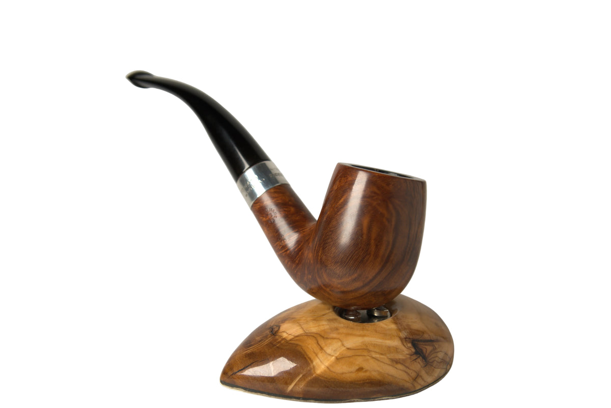 A handcrafted smoking pipe with a polished dark brown wood bowl, a curved black stem, and a silver band, displayed on a matching carved wooden stand against a neutral light gray background.