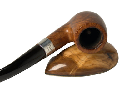 A close-up studio shot of a smoking pipe resting on a polished wooden stand against a light gray background.