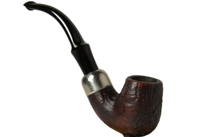 A smoking pipe with a dark brown carved wooden bowl, a silver metal collar, and a curved black stem, displayed on a polished natural wood stand against a neutral gray background.