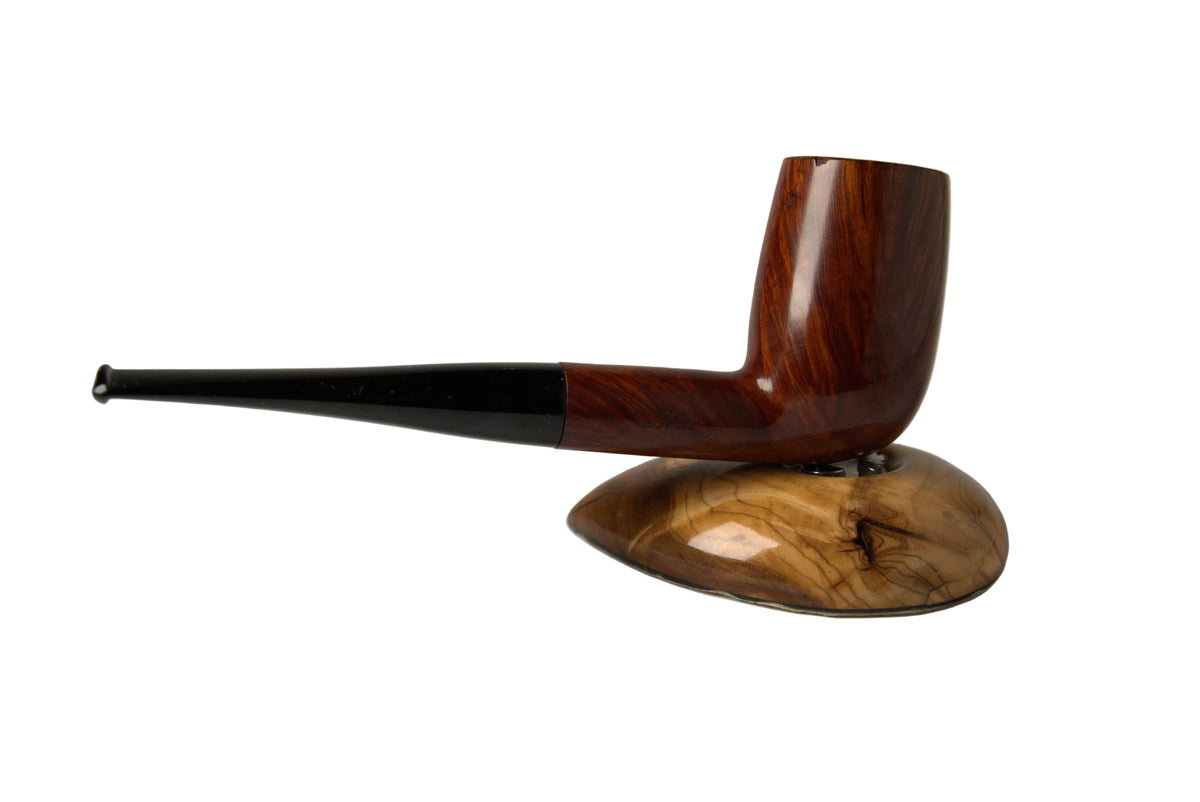 A polished wooden smoking pipe with a dark brown body, black stem, and a carved wooden base, photographed on a neutral gray studio background.