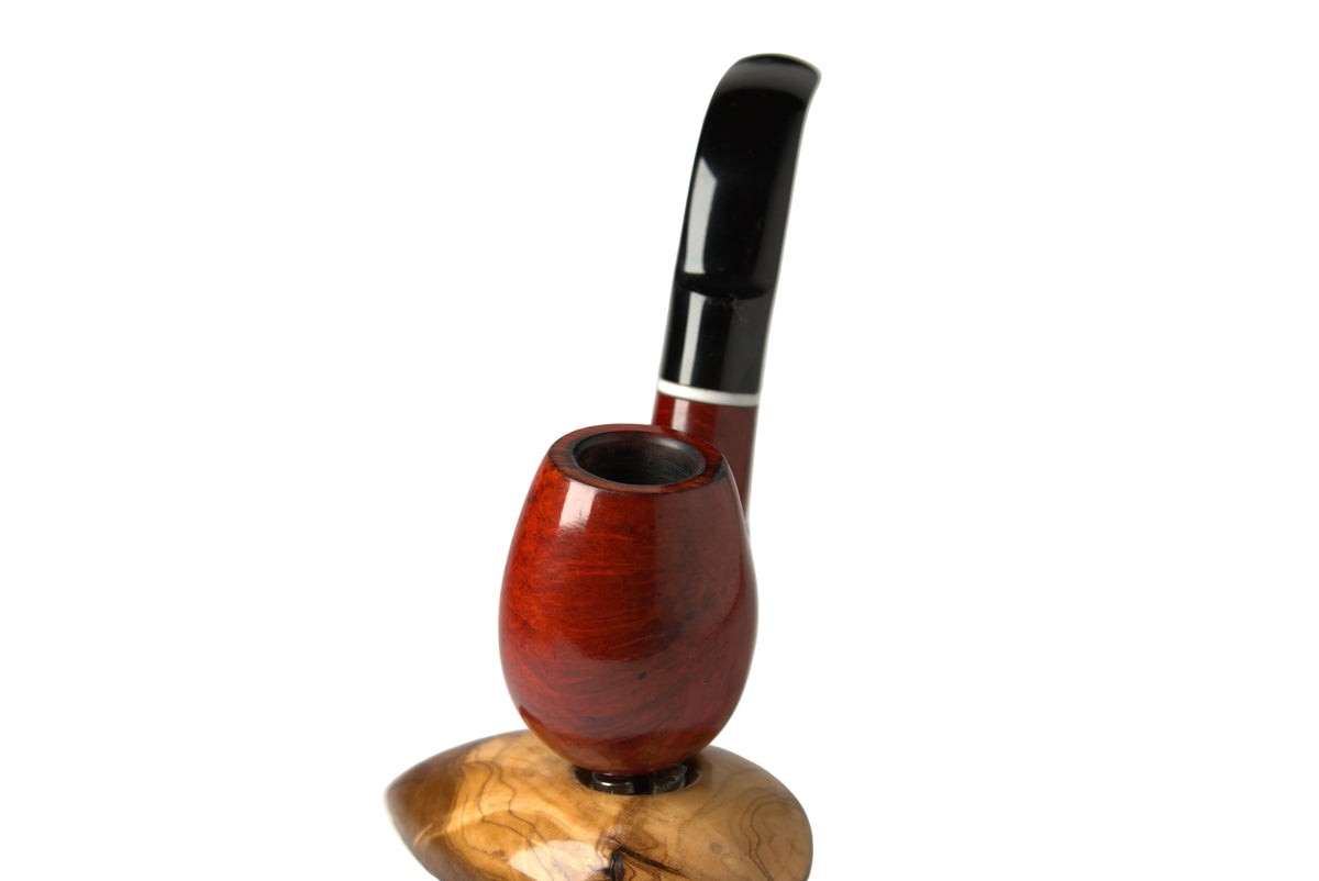 A smoking pipe with a glossy reddish-brown wooden bowl and a curved black stem, displayed on a polished wooden stand against a neutral gray background.