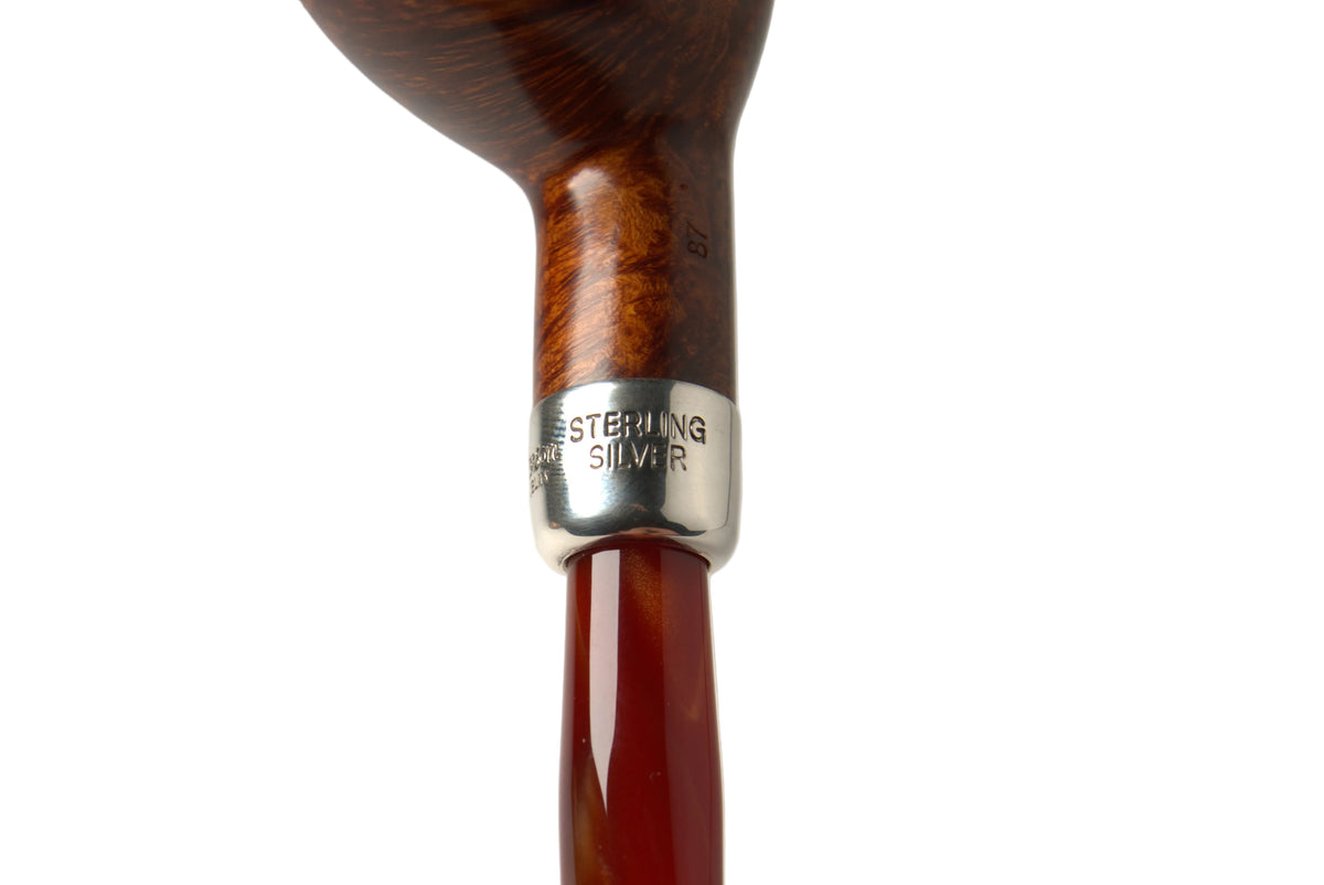 Close-up of a smoking pipe with a polished brown wooden bowl, a silver band engraved 'WESTERN DIGITALS 1945', and a reddish-brown translucent stem against a light gray background.