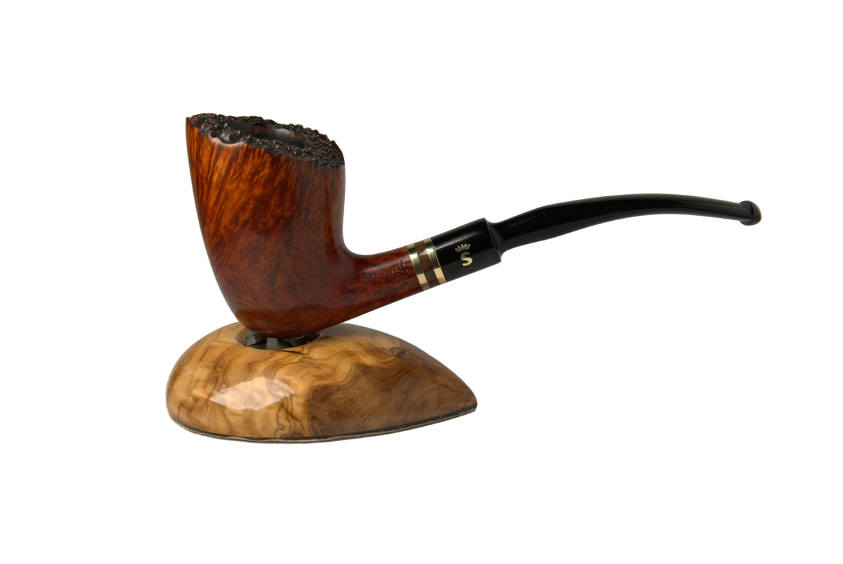 A smoking pipe with a polished reddish-brown wooden bowl and a long black stem, displayed on a carved wooden stand against a neutral gray studio background.