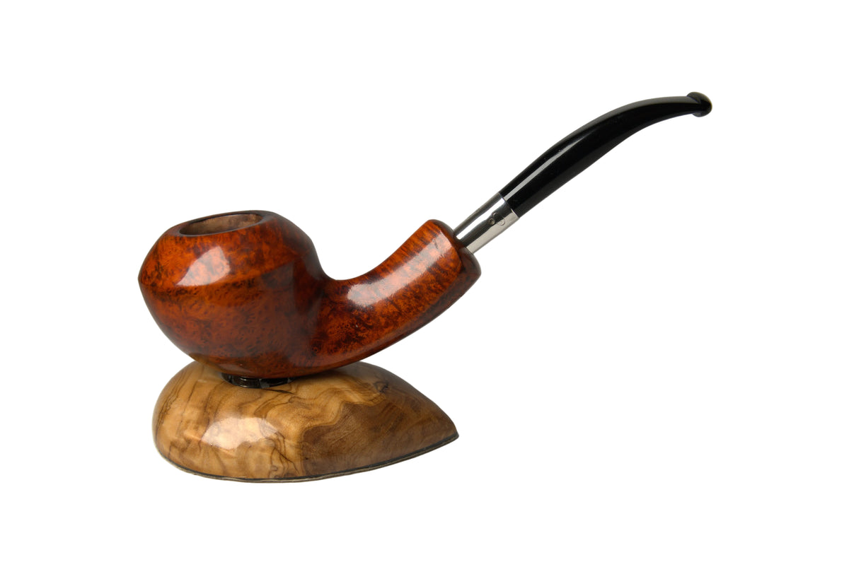A smoking pipe with a polished reddish-brown wooden bowl and a black stem, displayed on a matching carved wooden stand against a neutral gray background.