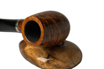 A smoking pipe with a richly grained brown wooden bowl and a black stem, resting on a matching polished wooden stand against a neutral gray background.