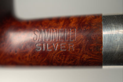 Close-up of a Savinele Silver smoking pipe showing the polished brown burl wood bowl and a silver metal stem against a light gray background.