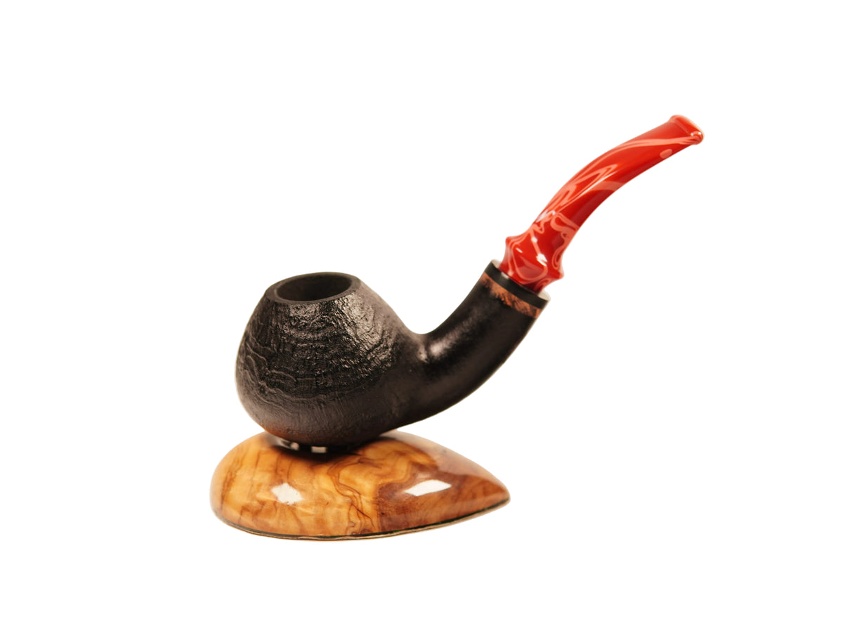 A smoking pipe with a dark textured bowl, a glossy red curved stem, and a polished wood base, photographed on a clean off-white background.