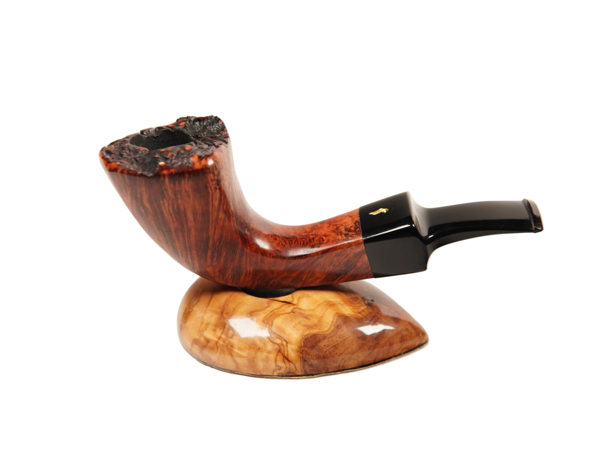 A handcrafted smoking pipe with a polished reddish-brown wood bowl, dark stem, and black ferrule, displayed on a matching carved wooden stand against a clean white background.