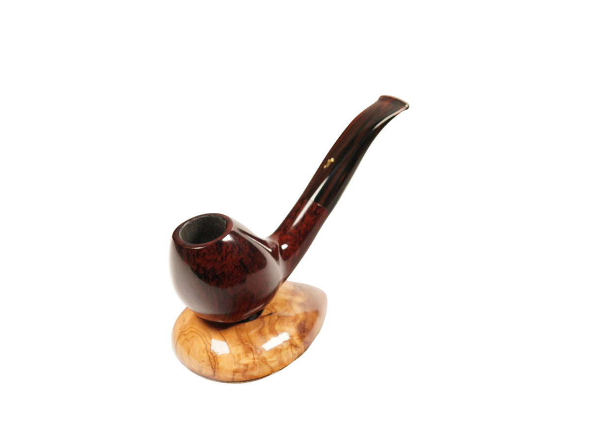 A polished smoking pipe with a dark reddish-brown bowl and stem, resting on a light tan marbled wooden stand against a plain white background.