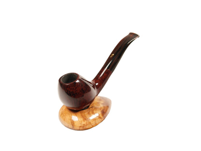 A polished smoking pipe with a dark reddish-brown bowl and stem, resting on a light tan marbled wooden stand against a plain white background.
