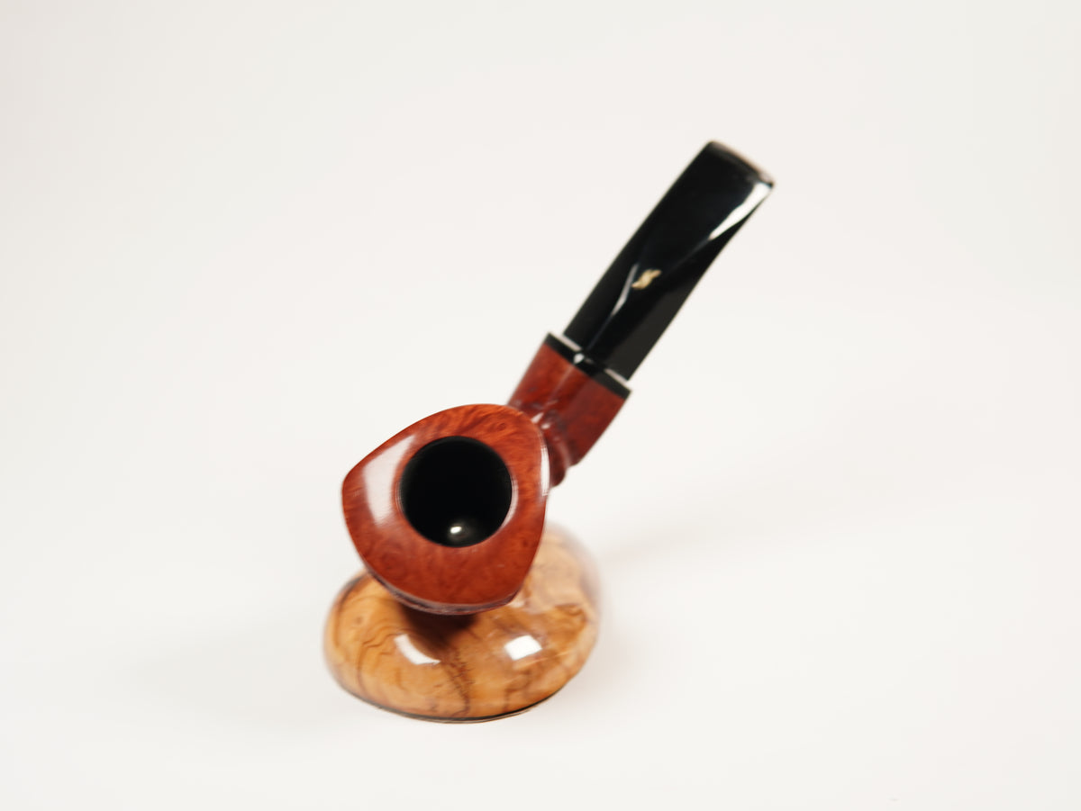 A smoking pipe with a polished reddish-brown wooden bowl and a glossy black stem, displayed on a matching wooden stand against a plain white background.