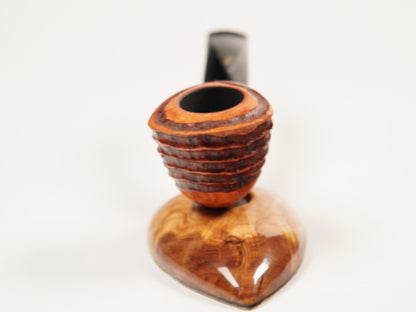 A close-up of a smoking pipe with a carved wooden bowl and a dark stem, set against a plain white background.