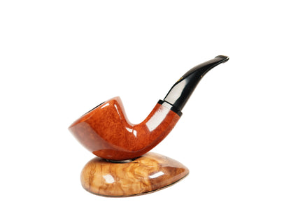 A polished smoking pipe with a warm orange-brown wooden bowl and a black curved stem, displayed on a matching carved wooden stand against a clean white background.
