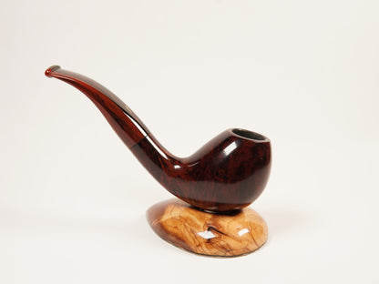 A polished dark brown wooden smoking pipe with a curved stem, displayed on a matching carved wooden base against a plain white background.