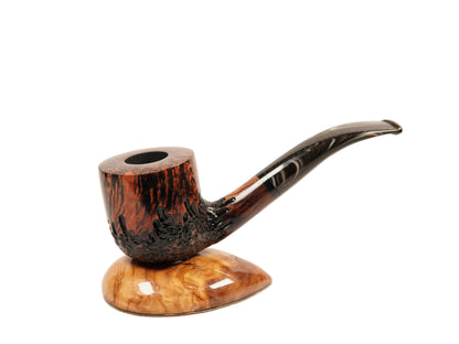 A handcrafted smoking pipe with a dark brown and black burl wood body and a curved stem, resting on a polished oval wooden base against a plain white background.