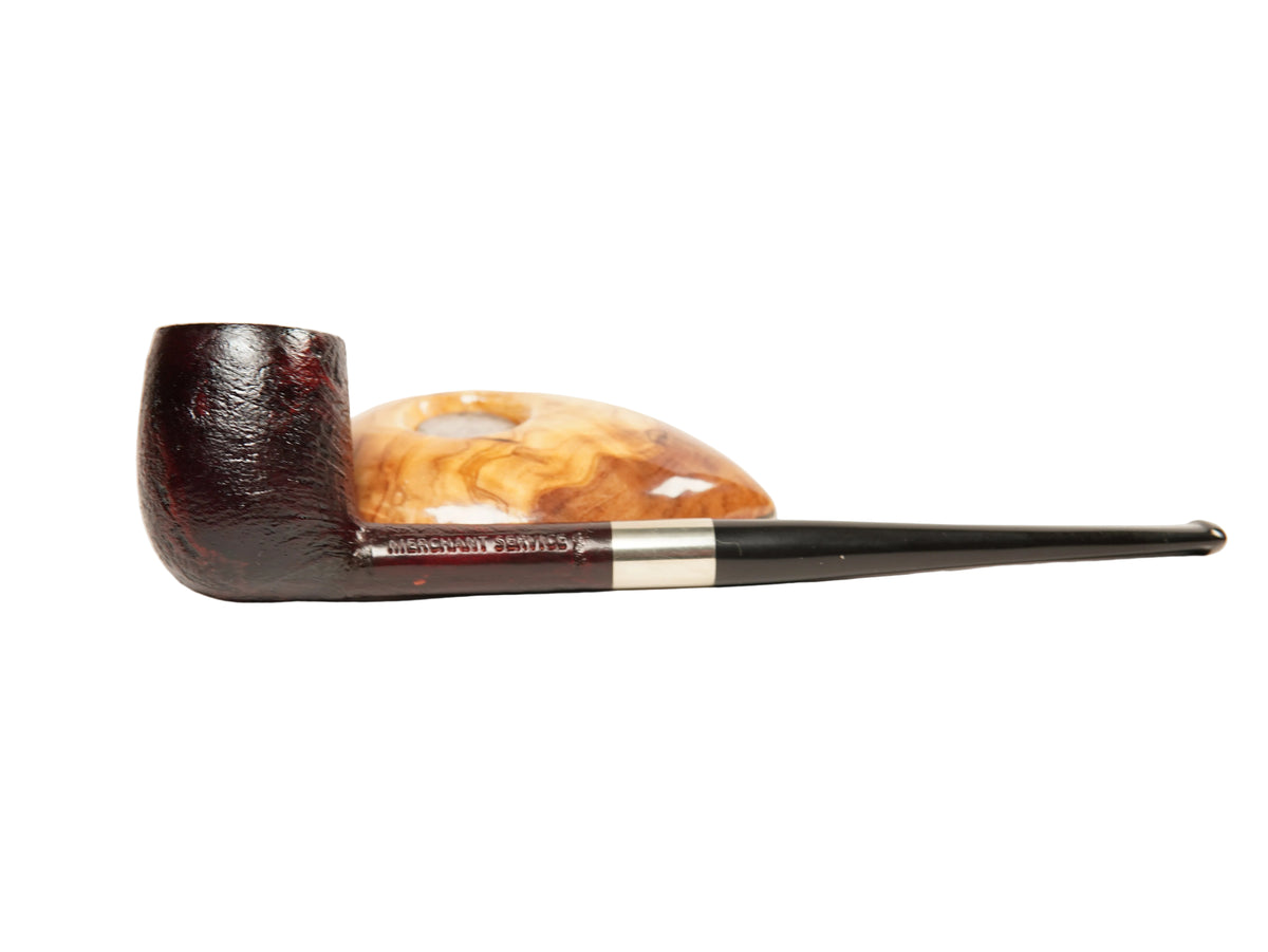 A smoking pipe with a dark brown carved bowl and a long black stem with a silver band, resting on a polished amber-colored stone against a plain white background.