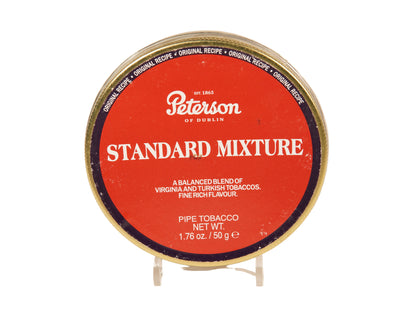 A round tin of Peterson of Dublin Standard Mixture pipe tobacco on a small clear display stand against a plain light background.