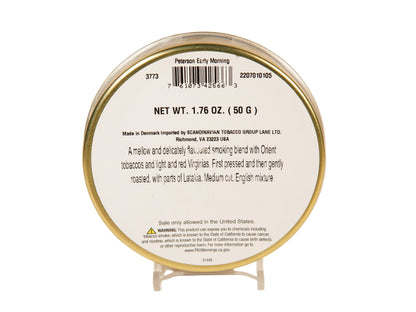 Back side of a round tobacco product tin on a small clear display stand, with printed text and barcode visible against a plain light background.